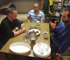 Chris, Josh and Steve sitting at the table in Bauer Bay hut sampling the entries in of the inaugural MIPEP Chocolate Slice Bake Off challenge