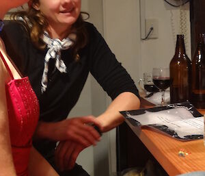 Angela wearing a red beret and a blue striped scarf, leaning against the bar