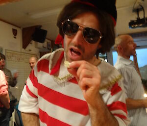 Stephen dressed as Napoléon in a red and white striped shirt wearing glasses leaning towards the camera holding cheese