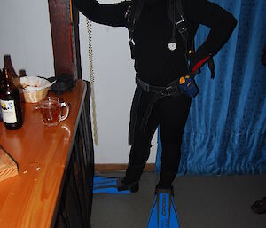 Chris dressed up as a French diver holding on to the side of the bar a phone behind blue curtain him and a phone is attached to the wall.