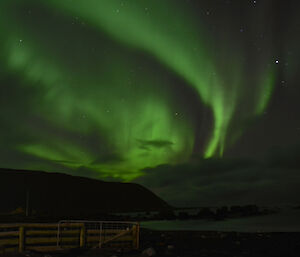 Green tinged aurora in the western sky, with the island hills silhouetted. There is a greenish reflection off the low clouds and the waters of Hasselborough Bay. The stars of the ‘big dipper’ can be seen in the top right of the sky