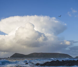 View across Hasselborough Bay at a well developed cumulonimbus cloud (thunderstorm cloud shaped like a mushroom) behind North Head. There are 2 sea birds in flight at the top of the photo. Also there is a rocky point in the foreground