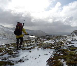 Tom walking with his back towards the camera, making his way up the snowy caped Plateau. Tom is wearing his red pack.