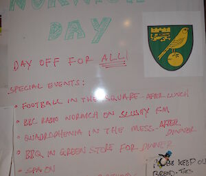 White board with writting on it saying Norwich, a day off for all, special events for the day;Football in the square after lunch,BBC Radio Norwich on Slushy FM,Quadrophenia in the mess after dinner,BBQ in Greenstore for dinner, SPA on and also it’s Tony’s Birthdays