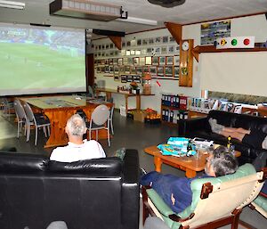 Several expeditioners watching the FA Cup final projected onto a big screen in the mess