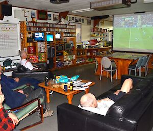 Several expeditioners watching the FA Cup final projected onto a big screen in the mess