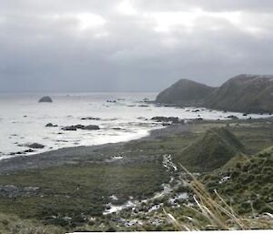 Panoramic view from a Docotors track looking towards the northern part of the island with the ocean on both sides the sky is cloudy and grey and in the distance you can make out the station.