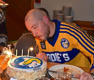 Craig sitting at the blowing out his birthday cake candles and sparlers