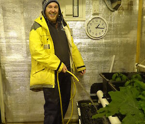 Aaron with the hose in his hand putting water into a hydroponics tank