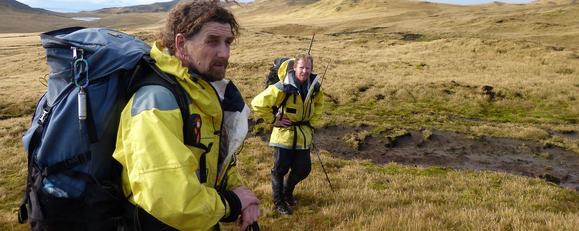 MIPEP Hunters Mike and Billy dressed in yellow AAD jackets with backpacks on, on top of the plateau, Macquarie Island