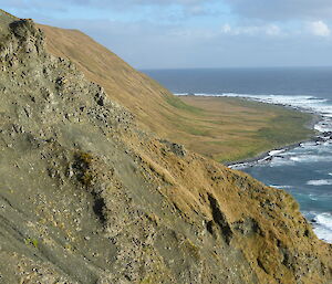 Hunter Karen Andrew is just visible as a dot mid screen climbing a jagged hill above the foreshore tussock and ocean extending to Handspike Point on the west coast of Macquarie Island.