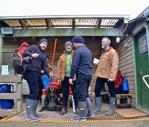 Four expeditioners on the porch of the mess getting ready to go to the boat shed