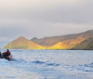 From one of the boats looking south along the rugged coast, with sun illuminating part of the hills in bright shades of green