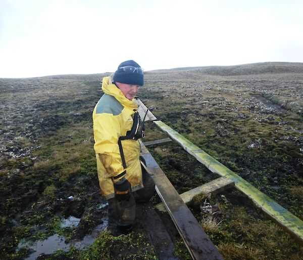 Chris, standing almost knee deep in mud and next to some unfinished boardwalk, pausing for a moment to work out the best way to get the job done