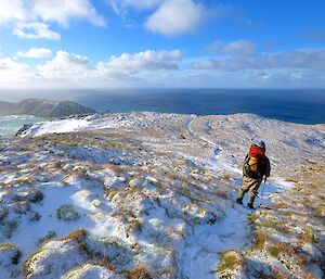 View of the snow covered Doctors Track with Aaron on the track just ahead. North Head and the Southern Ocean can be seen beyond the slopes