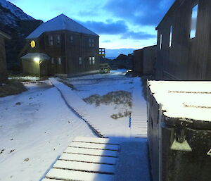 Hass house the court yard and the walking path covered in snow. The sun is rising