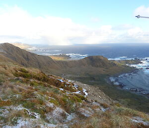 Mountain range and the ocean on the right a pointing pole