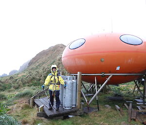 Paty standing outside of Brothers Point Googy accommodation wearing her gear holding her piles