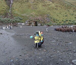 Patty crouching down near the old Sandy Bay hut and Penguin colony