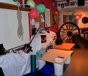 The Mess set up as an outback with a wagon wheel in the back ground tussock grass shovel some matts old bottles and cans there are some balloons coloured red, green and light green.