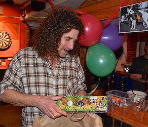 Billy with a brown paper bag — holding a plastic package containing 5 dog finger puppets