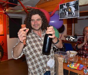 Billy holding a wooden bottle opener after just using it to open a bottle