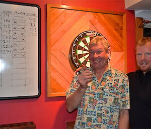 Dave and Mike (who filled in for an absent John) standing in front of the dart board and scoreboard, after one of the preliminary matches