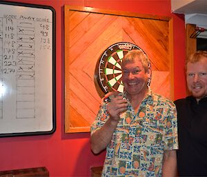 Dave and Mike (who filled in for an absent John) standing in front of the dart board and scoreboard, after one of the preliminary matches