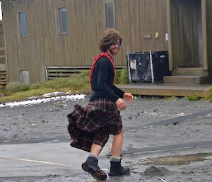 Dean, wearing a tartan kilt, wig and blue marks painted on his face, trying to dodge an incoming haggis