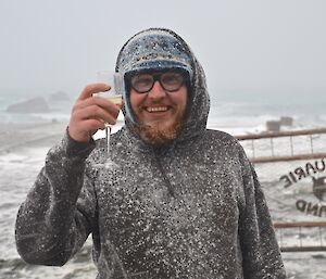 Aaron, covered in snow, celebrates the winner, standing in the driving snow and wearing protective glasses