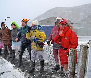 The trainers at the finish line, ready to start the race. They are being pelted by snow in the fierce wind