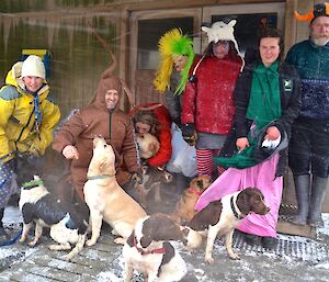 After the race — The seven trainers sheltering with 8 of the dogs under the porch of the workshop, while the snow is blown all around them