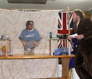 Aaron, standing to the side of the table, asking Bernard "what is the first thing you do after getting up?"