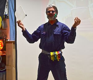 Clive, the Waste Minimisation Officer shows the audience a couple of plastic lids. He is wearing his new belt tape dispenser