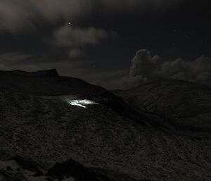 Mike Fawcett spotlighting — taken at night shows the weak lit landscape on the plateau with a bright patch illuminated by the head torch of Mike