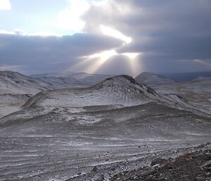 Looking north form Eifold across the partially snow covered rolling hills, with the sun producing rays (crepuscular Rays) through the scattered cloud