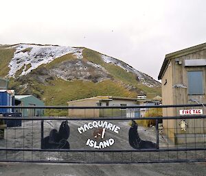 The revamped Macca gate seen from outside the enclosure. The gate is painted black and the central panel has a fur seal silhouette on the left and a elephant seal on the right, while in the middle is the words Macquarie Island surrounding a small world map, with some images on it (painted white)