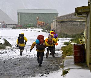 The ‘hasty’ team of Mike, Chris, Angela and Craig heading off past the station buildings to Gadgets Gully. They are all dressed in their wet weather gear, and carrying packs with survival and SAR gear. It is snowing