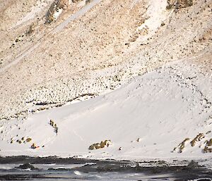 Taken from a distance — bathed in sunlight, the ERT (Emergency Response Team) start the climb up the snow covered slopes at the base of Gadgets Gully