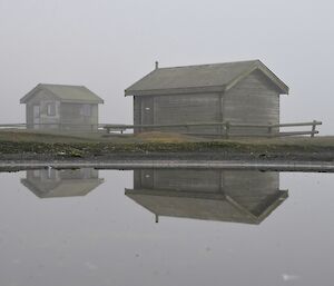A couple of days later — foggy and calm. Against a misty backdrop, two of the huts in the magnetic quiet zone reflected in a pond
