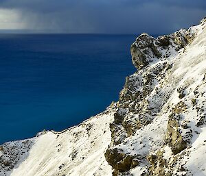 View from the top of Gadgets Gully — the foreground shows the snow covered slopes bright in the sunshine in contrast with the dark blue ocean in the background