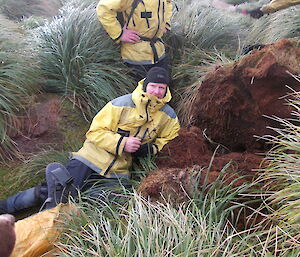 Mike, one of the MIPEP team next to a mound of brown dirt dug up from amongst the tussock. There is a rabbit carcass at the base of the mound. All tussock and dirt restored after the dig