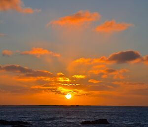 Sunset from West Beach — the clouds are shades of orange and yellow and frame the orb of the sun