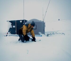 Ange, kneeling on the deep snow, about to start digging