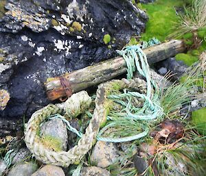 Shows a piece of timber, believed to be part of a spar associated with one of the many shipwrecks around the island. The spar has a rusted ‘collar’ at one end and a thick rope next to it
