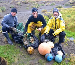 Chris, Barry and Clive squat behind the four bags of marine debris, which includes six fishing floats over various colours and sizes. This was all picked up from Bauer Bay and Boiler Rocks coast