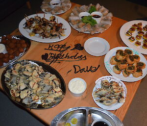 Finger food for Dave’s birthday spread out on the coffee table. ‘Happy Birthday Dave’ is spelled out in chocolate on the centre of the table