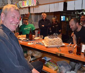 Dave, in the left foreground, enjoying his birthday while several other expeditioners congregate around the bar. The large birthday cake is on the bar