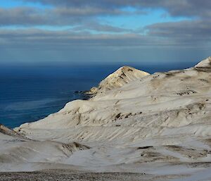 A view across a extensively snow covered scene from a high vantage point on the plateau towards Sandy Bay and Brothers Point contrasting with the deep blue coloured ocean