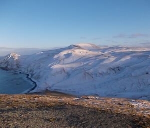 A view from a high vantage point above Sandy Bay to Brothers Point. The snow covered peaks are lit by the late afternoon sun